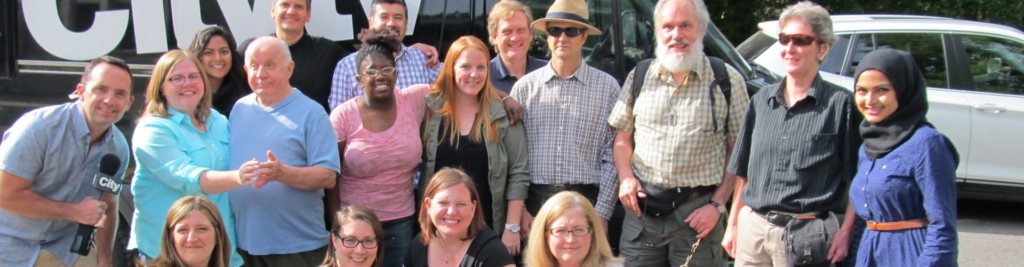 Group of individuals and their intervenor's lined up, smiling in front of a city TV van with Breakfast Television personality Frank Ferragine.