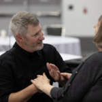 An intervenor and consumer communicate using hand-over-hand ASL.