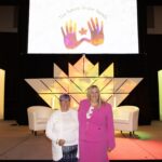 To the left is Cathy Proll, CEO of Sensity and standing next to her is Jennifer Robbins, Executive Director, CHKC. They stand to in front of the main podium at the Shaw Centre in Ottawa, Canada.